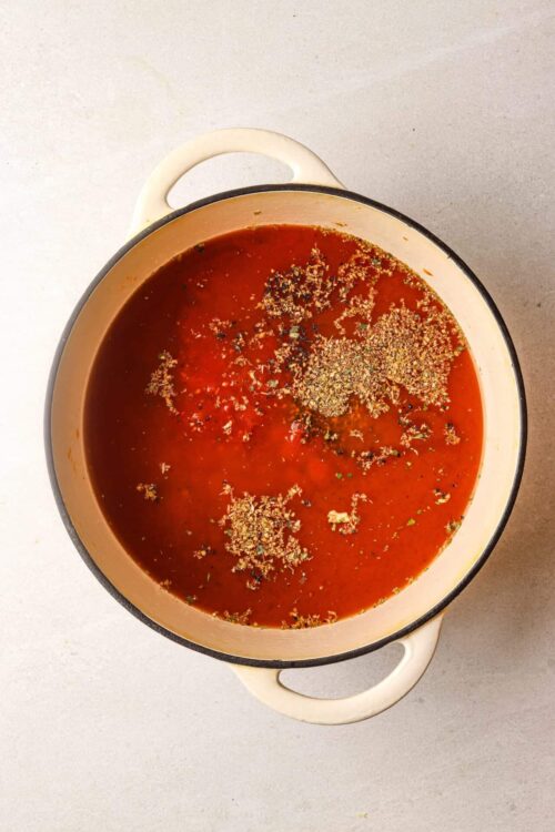Hearty homemade tomato soup with spices and herbs in a vintage enamel pot.