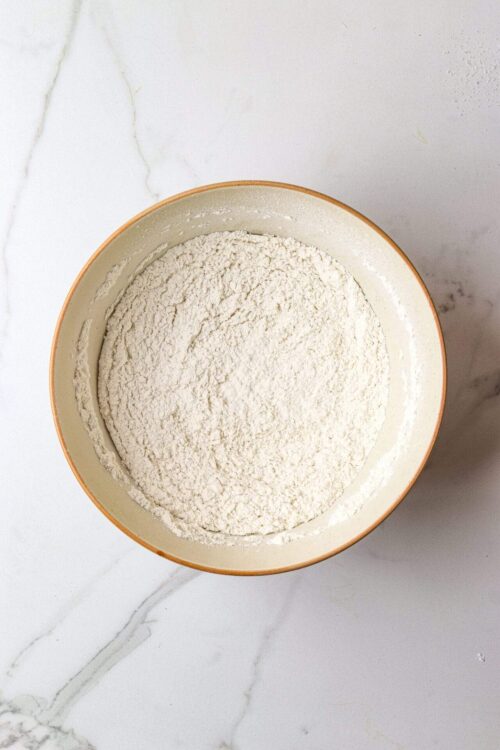 Flour in a beige mixing bowl for baking recipes.