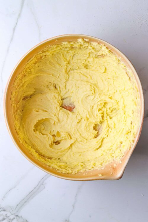Creamy, freshly made butter in a mixing bowl with a smooth, yellow texture.