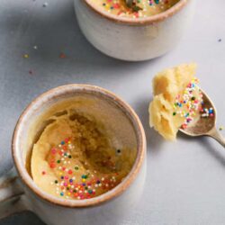 Creamy vanilla mug cake with colorful sprinkles on top.