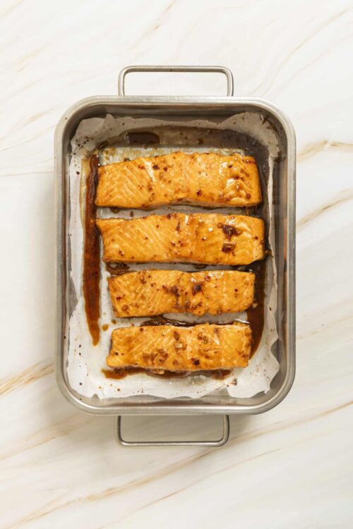 Baked salmon fillets with glaze on baking sheet, healthy seafood recipe.