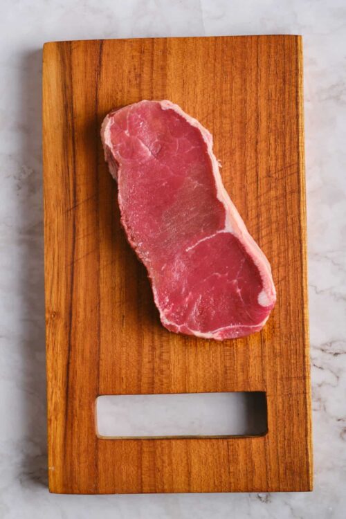 Raw pork chop on wooden cutting board.