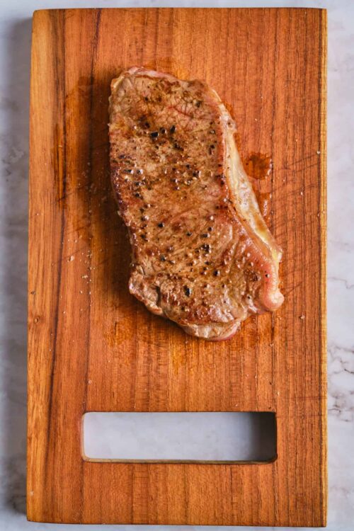 Juicy, seasoned steak on wooden cutting board, perfect for Baked Bree's delicious recipes.