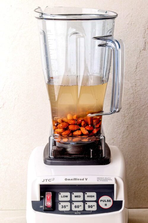 Almonds soaking in water in a blender for almond milk recipe.