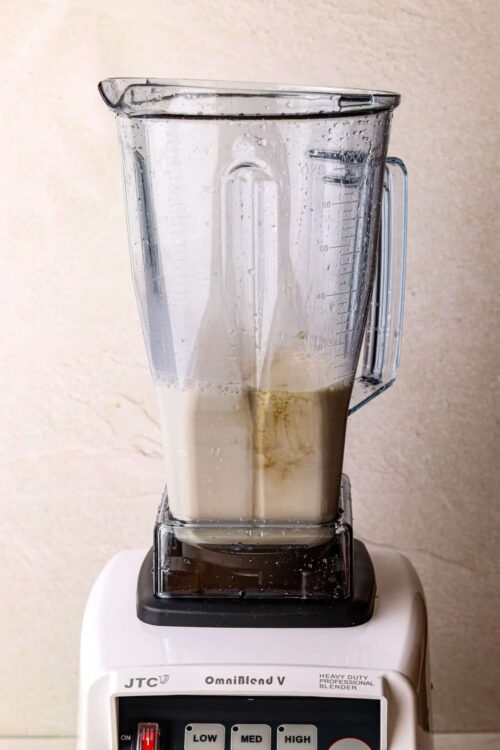 Blended milkshake in a blender with remnants of banana and milk on the sides.