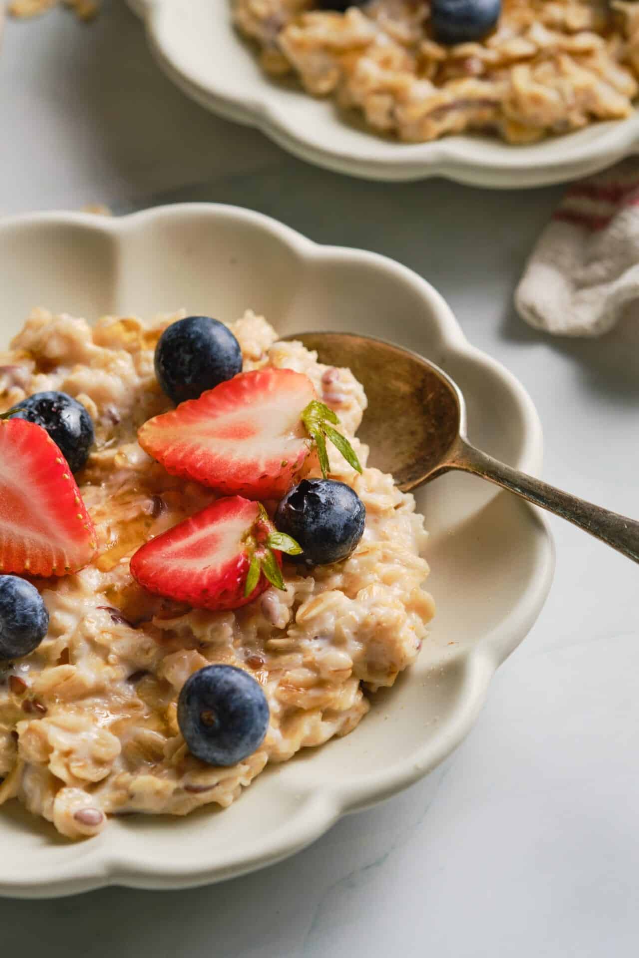 Creamy oatmeal topped with fresh strawberries and blueberries in a white ceramic bowl.