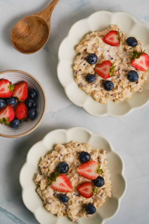 Fresh strawberry and blueberry oatmeal served in scalloped ceramic bowls for a healthy breakfast option.