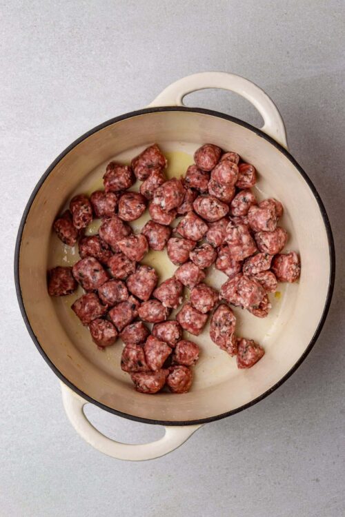Juicy sausage meatballs cooking in a cast iron skillet for delicious recipes.