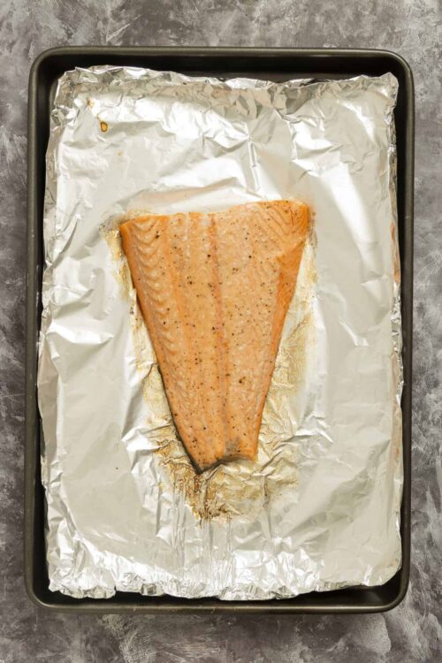 Baked salmon fillet on foil-lined baking sheet ready for oven.
