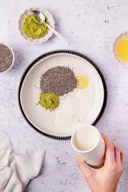 Ground chia seeds, matcha powder, and coconut milk in a white bowl for healthy vegan recipes.