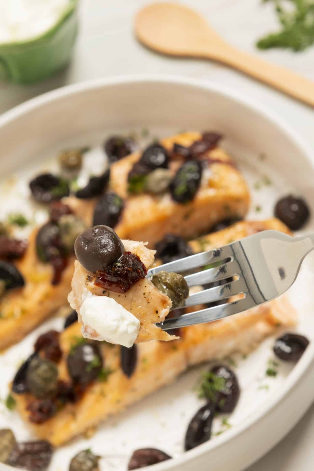 Creamy salmon with capers and olives on a white platter.