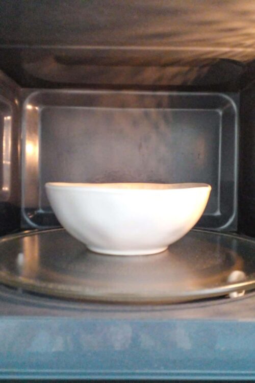 Microwave safe white ceramic bowl inside microwave oven.