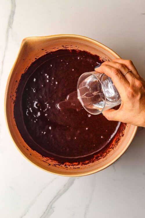 Rich chocolate sauce being poured into a bowl, perfect for baking recipes.