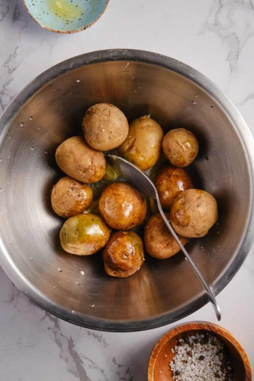 Boiled new potatoes in stainless steel bowl with salt and herbs.