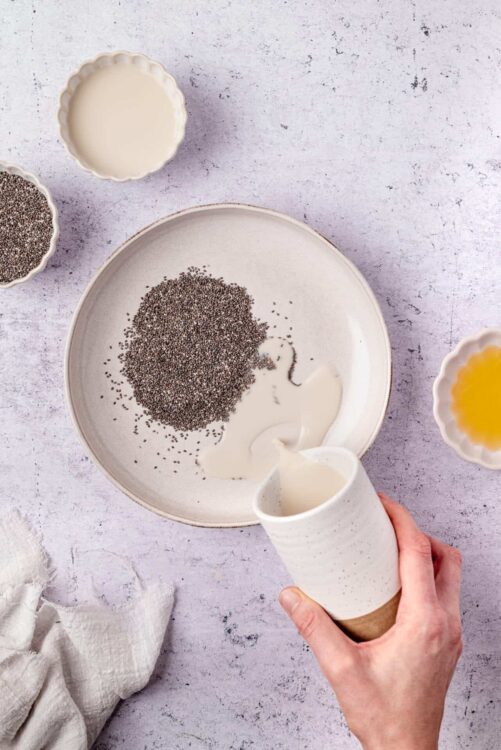 Poppy seeds being poured into milk in a bowl, baking ingredients, food preparation, baking process.