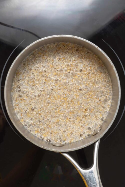 Creamy oat mixture simmering in a saucepan for healthy breakfast or oatmeal recipe.