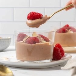 Creamy chocolate mousse topped with fresh raspberries on a glass dessert cup.