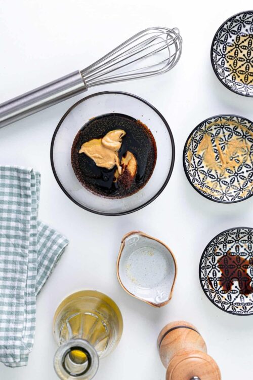 Rich soy sauce, peanut butter, and sesame oil in a glass bowl for Asian-inspired sauce.