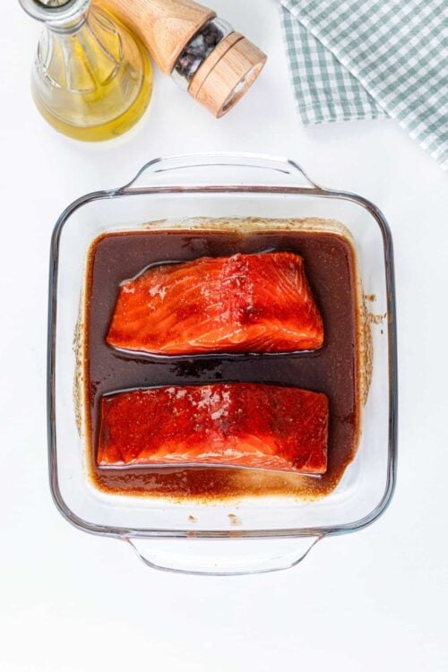 Juicy salmon fillets marinating in a flavorful soy sauce glaze in a glass baking dish. Perfect for healthy, easy salmon recipes.