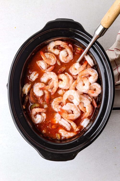 Juicy shrimp cooking in a flavorful tomato-based sauce in a slow cooker.