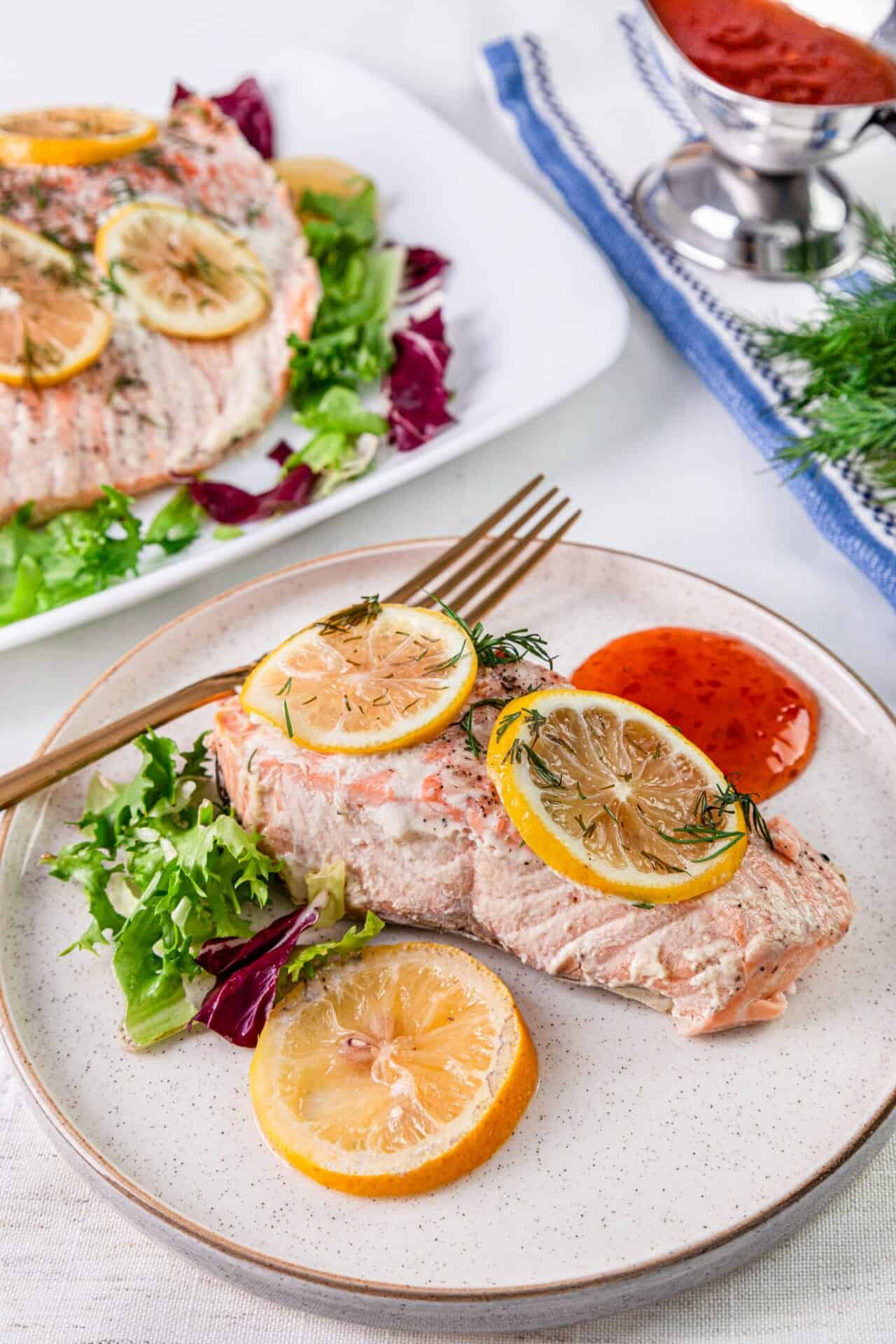 Succulent baked salmon with lemon and herbs served with fresh greens and a side of tangy tomato sauce. Easy, healthy dinner recipe.