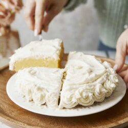 Buttercream frosting cake with white floral decoration on top.