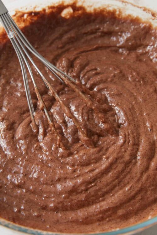Fudgy chocolate cake batter in a mixing bowl with a whisk.