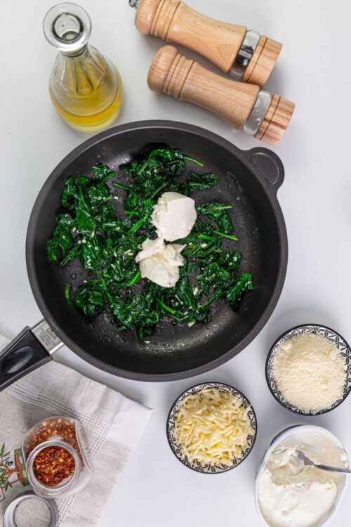 Sauteed spinach with garlic and cream in a black skillet.