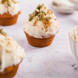 Sweet pumpkin muffin topped with creamy frosting and pumpkin seeds, perfect fall dessert.