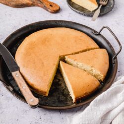 Buttermilk Pound Cake baked in a round pan with a slice served on a black plate.