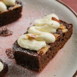 Decadent chocolate dessert with vanilla cream topping on a ceramic plate.