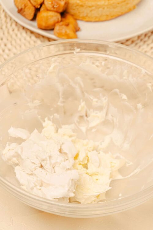 Cream cheese being whipped in a glass bowl for baking recipes.