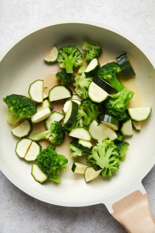 Sauteed zucchini and broccoli in a white skillet, ready for a healthy vegetable dish.