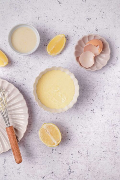Butter, lemons, eggs, and baking utensils for lemon cake batter preparation.