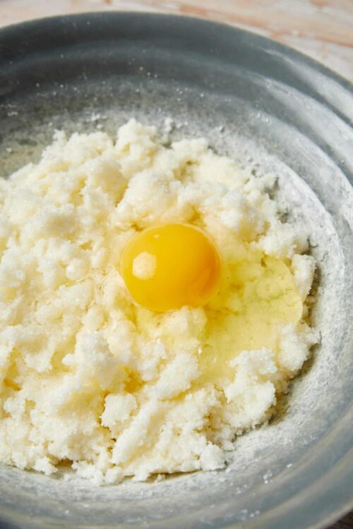 Butter, sugar, flour, and egg mixture for baking, close-up of ingredients in a metal bowl.