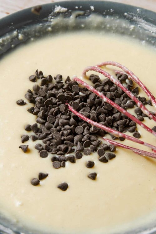 Creamy chocolate chip cookie dough in a mixing bowl with a pink whisk.