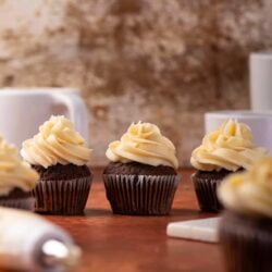 Delicious chocolate cupcakes with vanilla frosting on baking table.