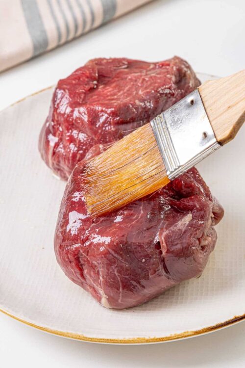 Raw beef tenderloin for roasting with basting brush.