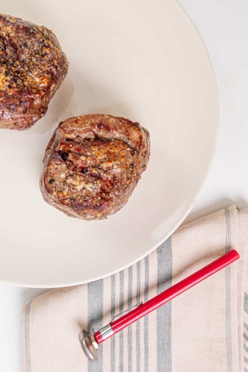 Succulent grilled beef tenderloin steak on white plate, close-up shot.
