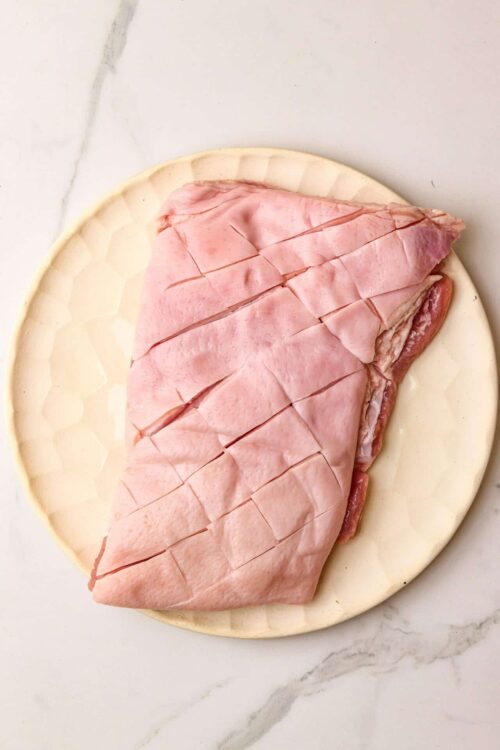 Thinly sliced ham on a ceramic plate, perfect for sandwiches or appetizers.