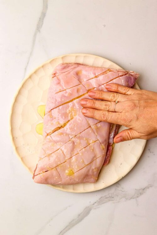 Sliced raw ham being prepared on a marble countertop.