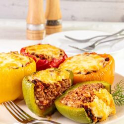 Stuffed bell peppers with ground meat, cheese, and rice, baked to perfection. Delicious and easy dinner or family meal idea.