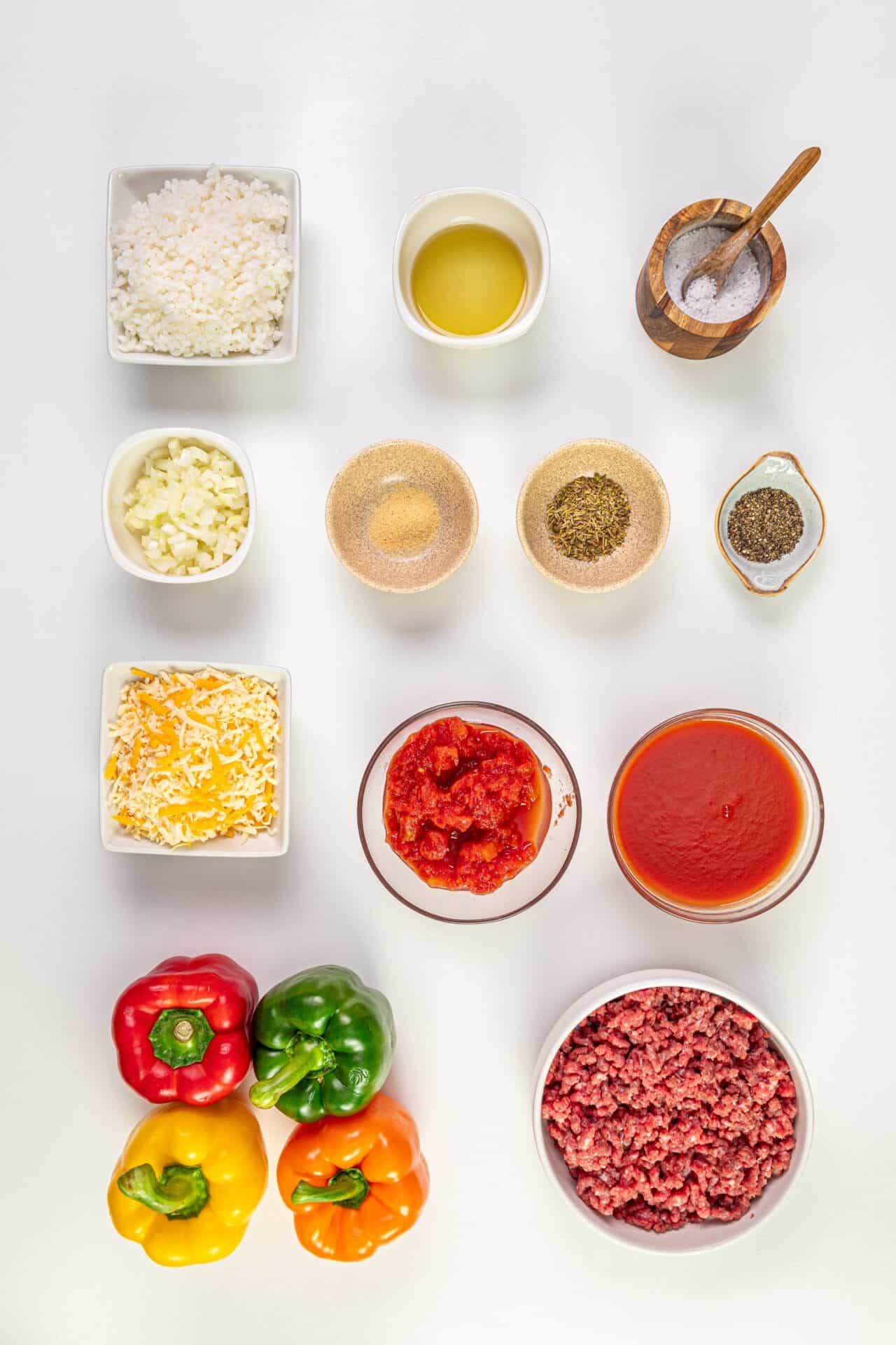 Colorful fresh bell peppers and ground beef with tomato sauce, cheese, and spices for delicious stuffed peppers recipe.