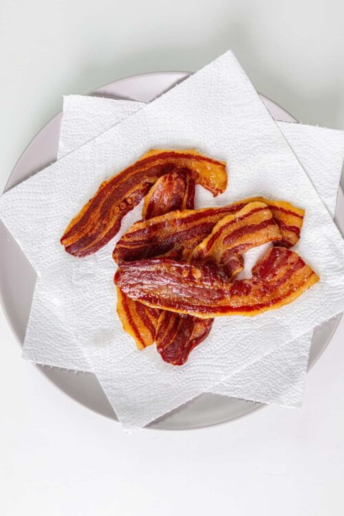 Crispy bacon strips on white paper towel, ready to serve.