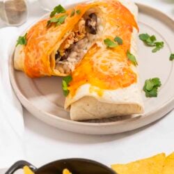 Cheesy chicken rice burrito casserole with melted cheese and fresh cilantro on a white plate.