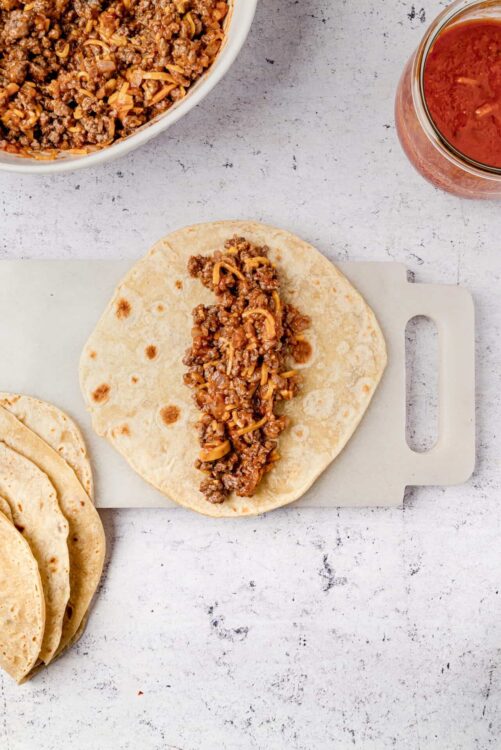 Savory beef and shredded cheese taco filling on a soft tortilla for homemade Mexican tacos.