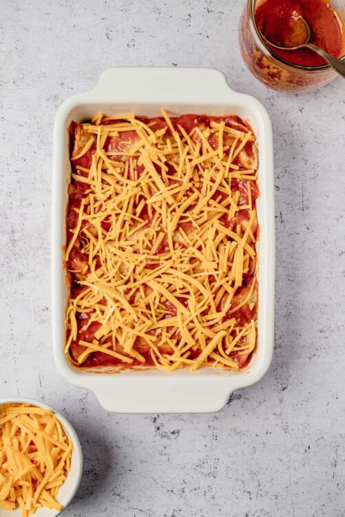 Cheesy baked Ziti casserole in white baking dish with shredded cheese on top.