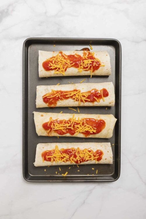 Baked cheese and tomato enchiladas on baking sheet.