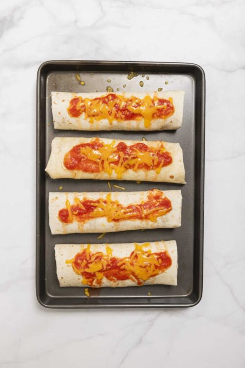 Cheesy vegetable-stuffed tortillas on baking sheet, ready to bake.