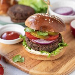 Juicy homemade beef burger with fresh vegetables on sesame bun.